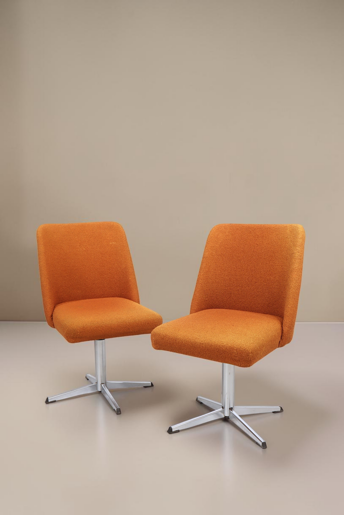 Zwei Vintage Space orangefarbene Mid-Century Drehstühle mit Aluminium-Sternfuß vor weißem Hintergrund