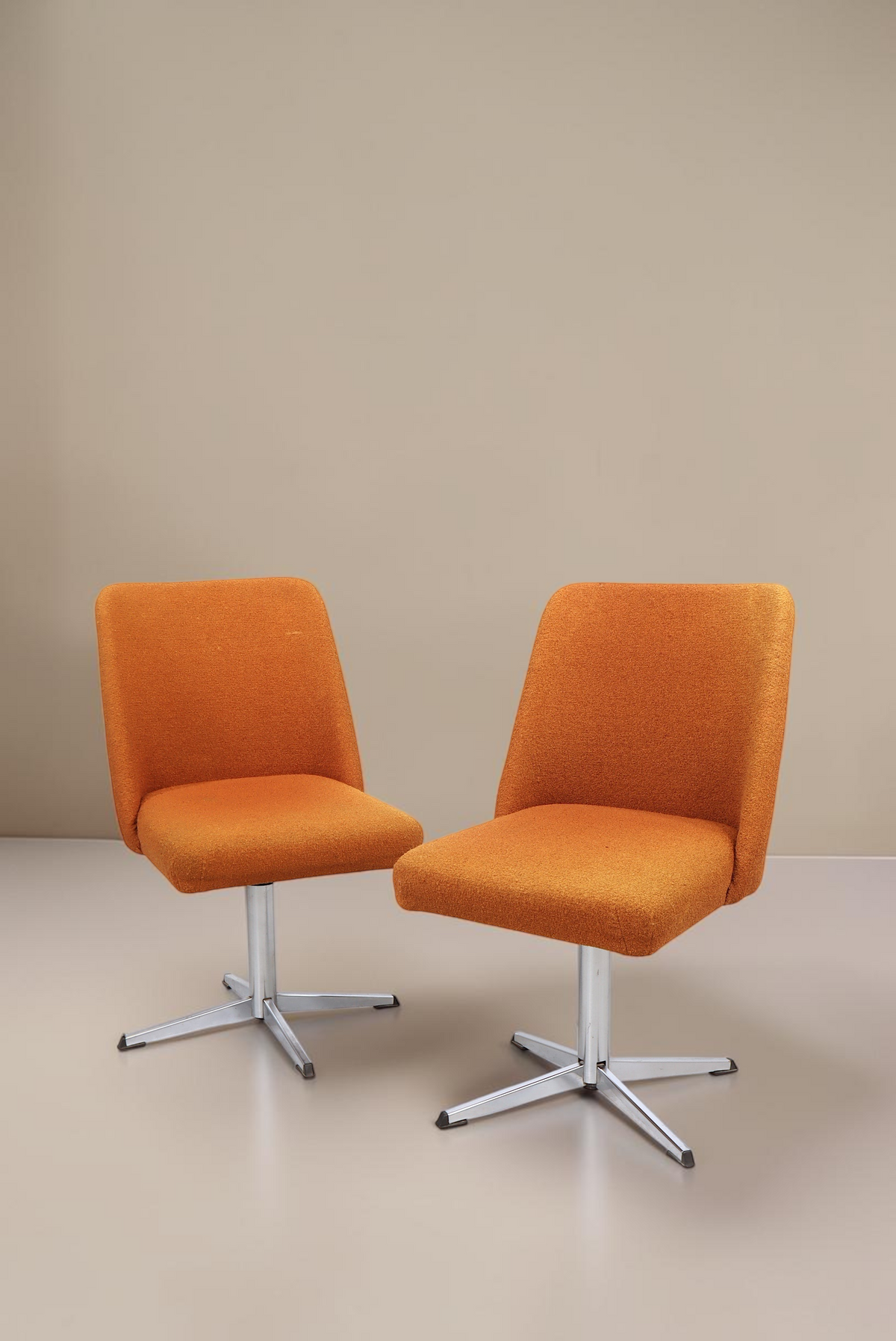 Zwei Vintage Space orangefarbene Mid-Century Drehstühle mit Aluminium-Sternfuß vor weißem Hintergrund