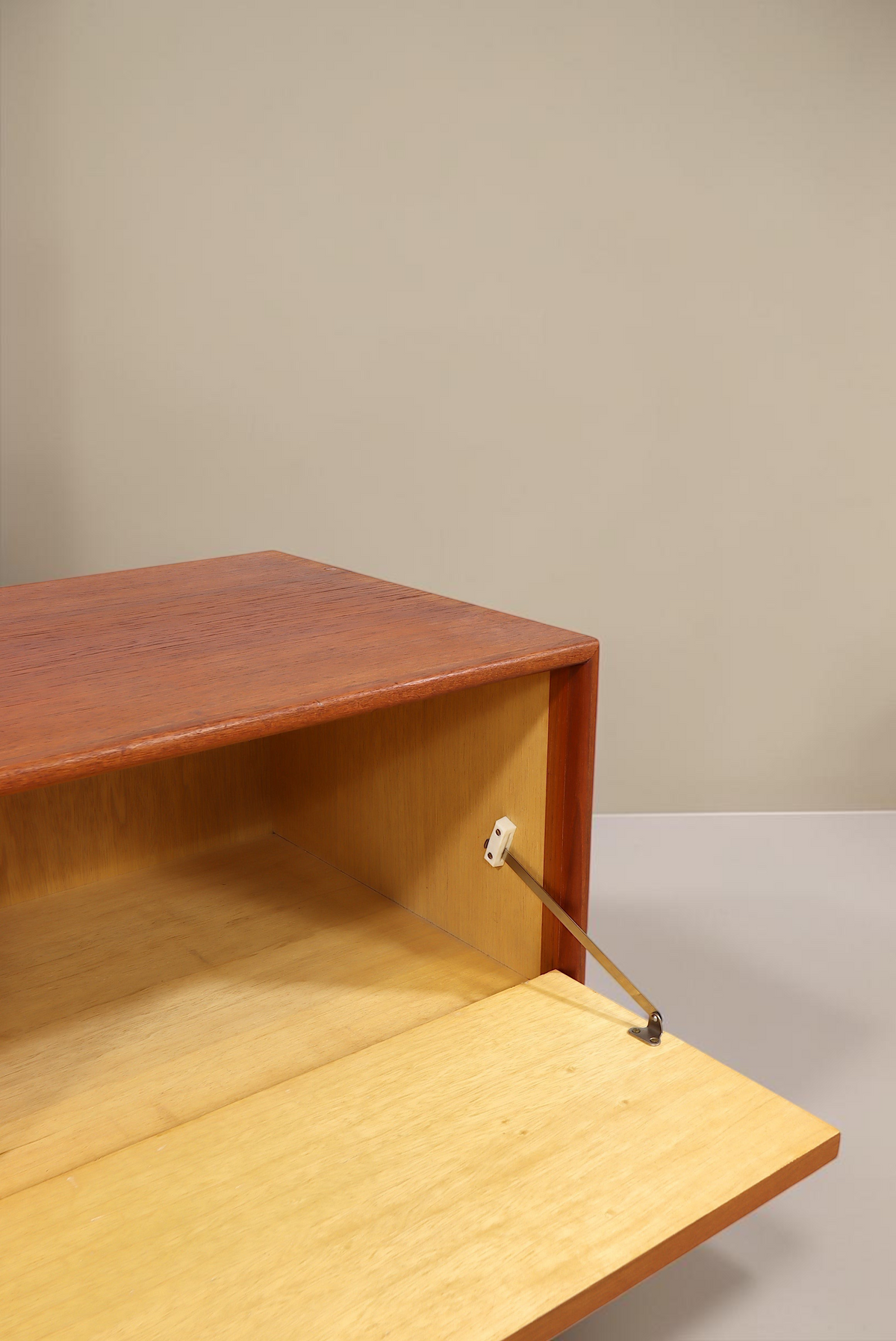 Vintage Space Mid Century Teak Sideboard mit geöffneter Klapptür und hellem Innenraum vor weißer Wand